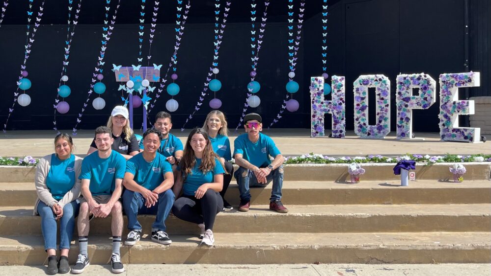 A group of volunteers sitting on stairs with the word hope next to them.